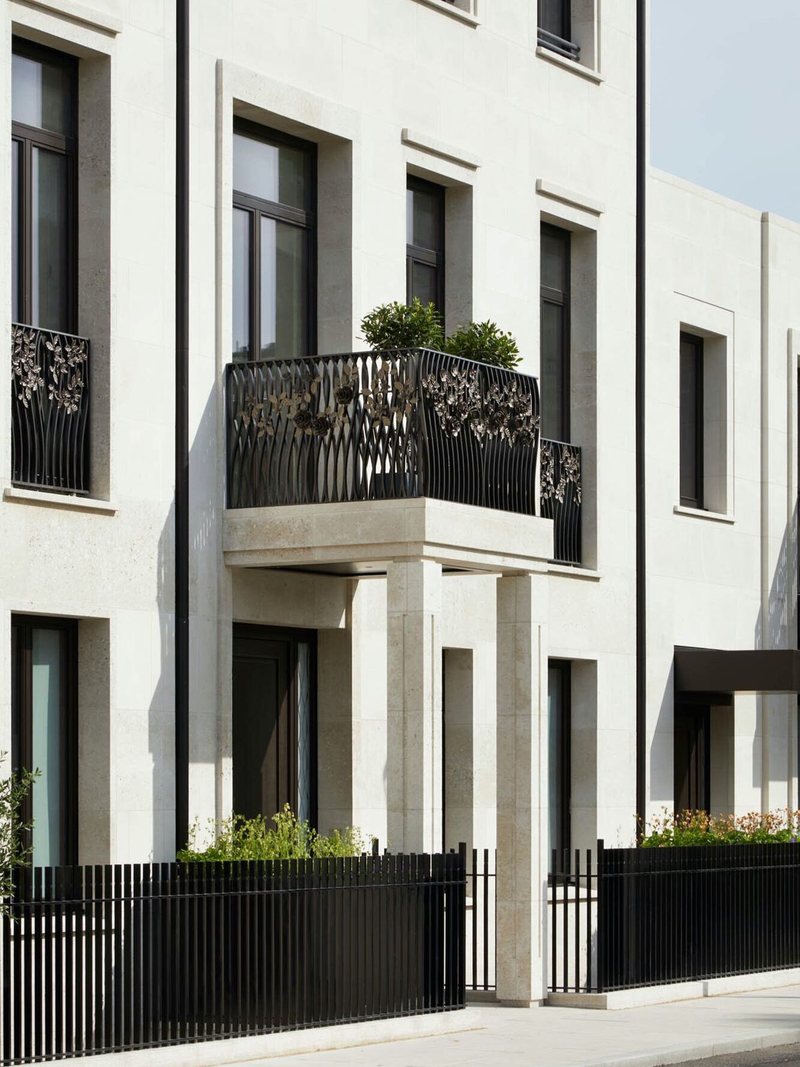 Pale-stone London townhouse with a sculpted iron balcony above a columned entrance