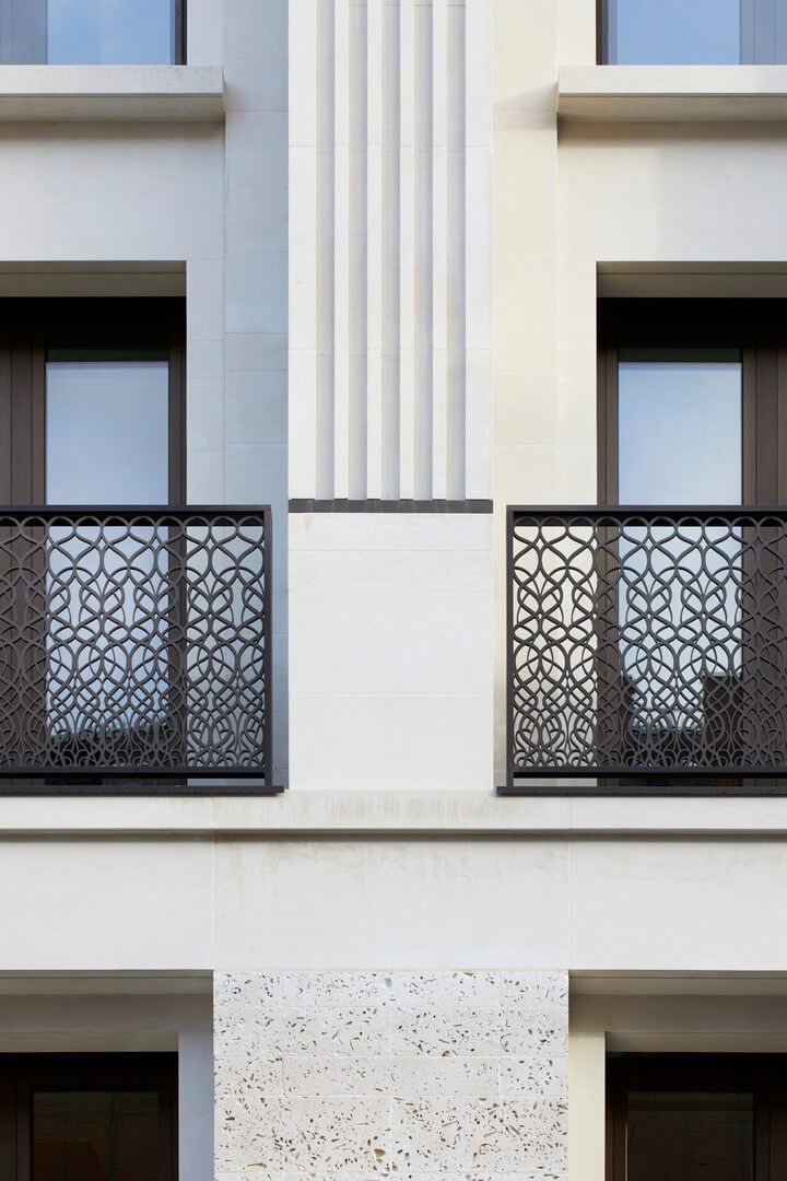 Stone facade with patterned black iron balconies