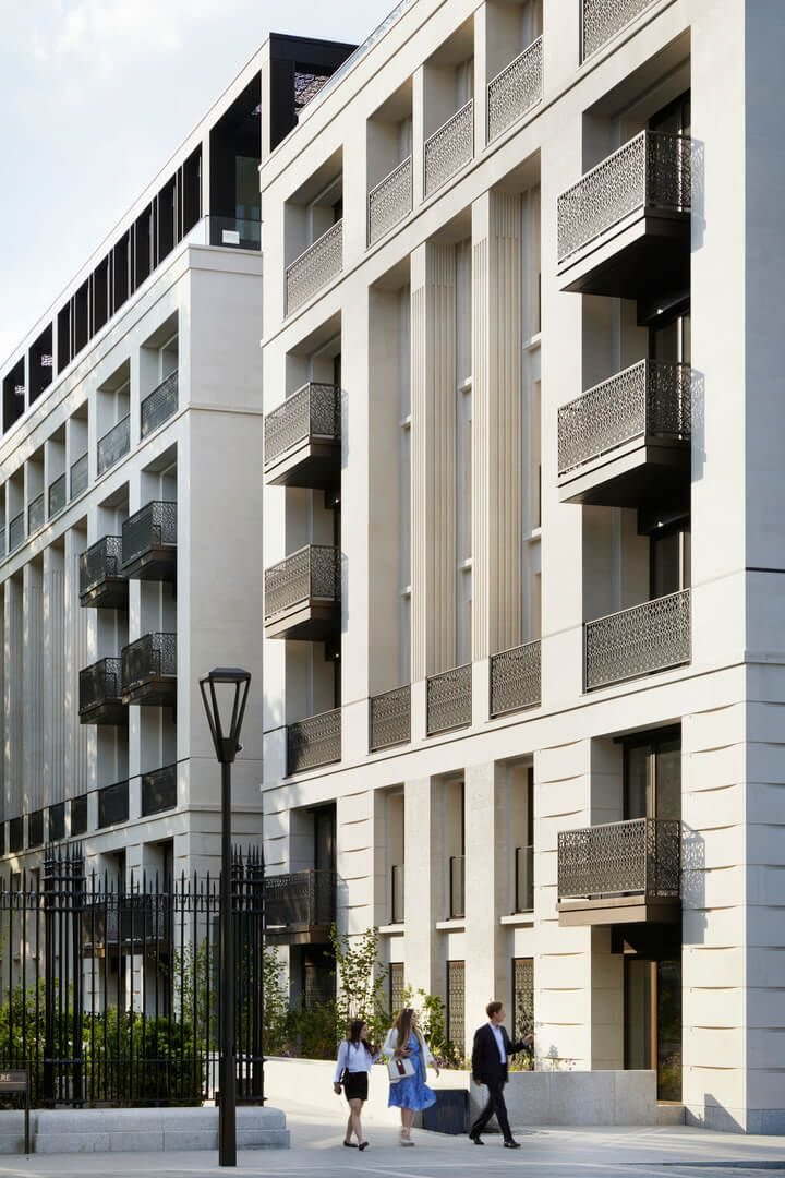 Pale-stone London apartment buildings with ornate balconies and residents walking along a tree-lined street
