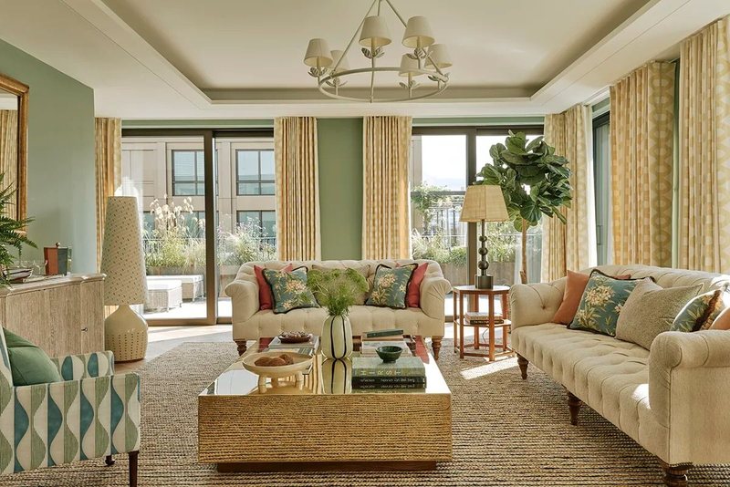 Living room with green walls, cream sofas and tall windows onto a terrace